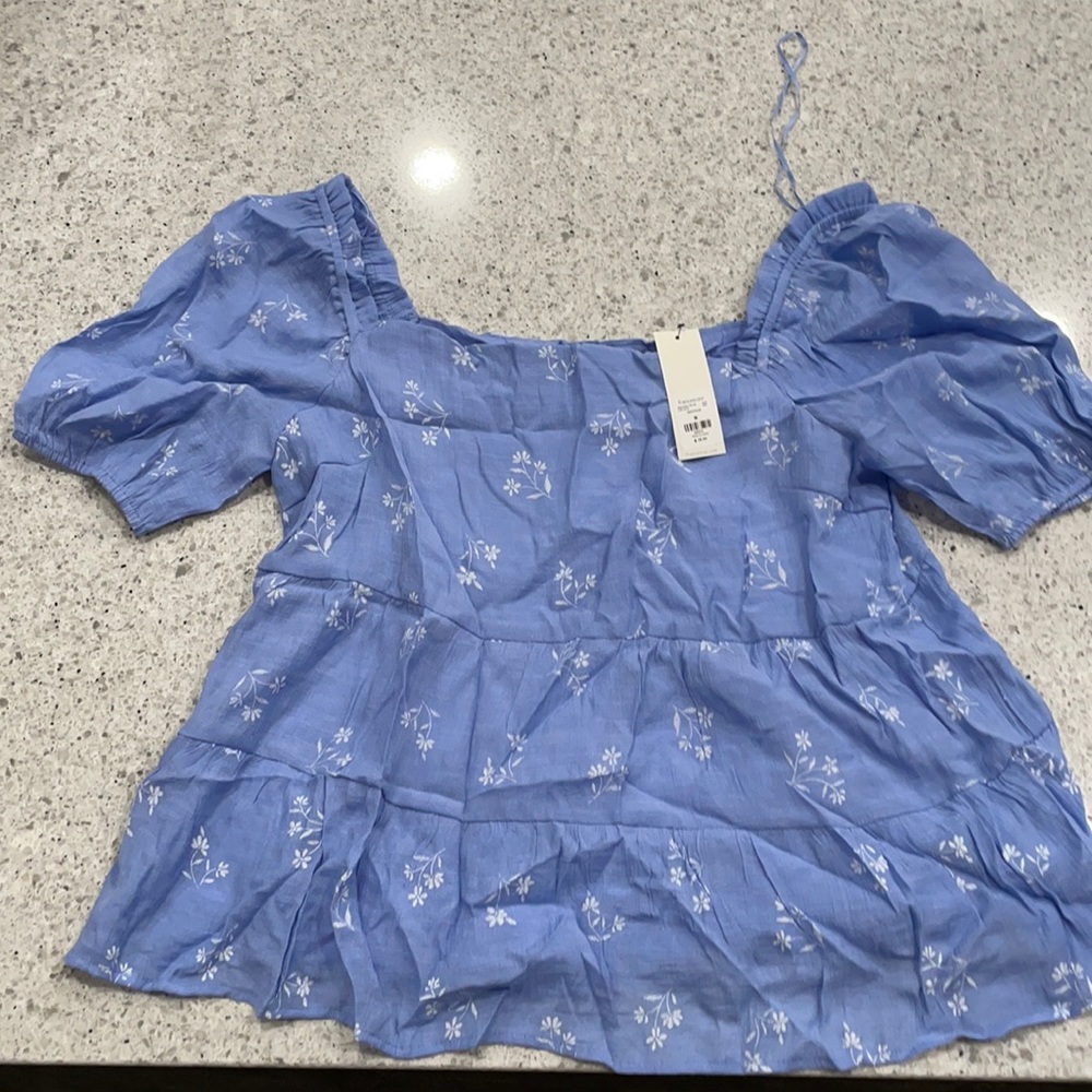 New with tags never worn blue blouse with white embroidered flowers.